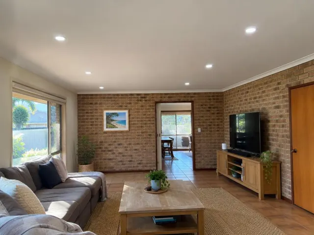 Living room with ceiling downlights, brick walls, tiled floor and sofa in Parkwood